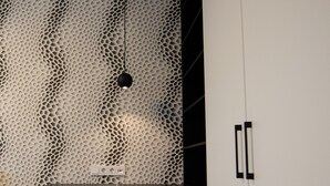 Una habitación moderna con un escritorio blanco, una silla color turquesa y una pared decorativa con un diseño de panal.