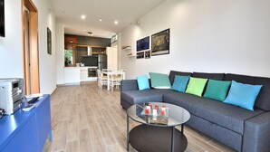 A modern living room with a grey sofa, a glass coffee table, and a blue cabinet.