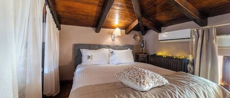 A bedroom with a wooden ceiling, a bed with white bedding, a headboard, and a wall-mounted lamp.