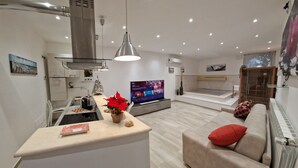 Un salon moderne avec un téléviseur, un canapé et un coin cuisine.