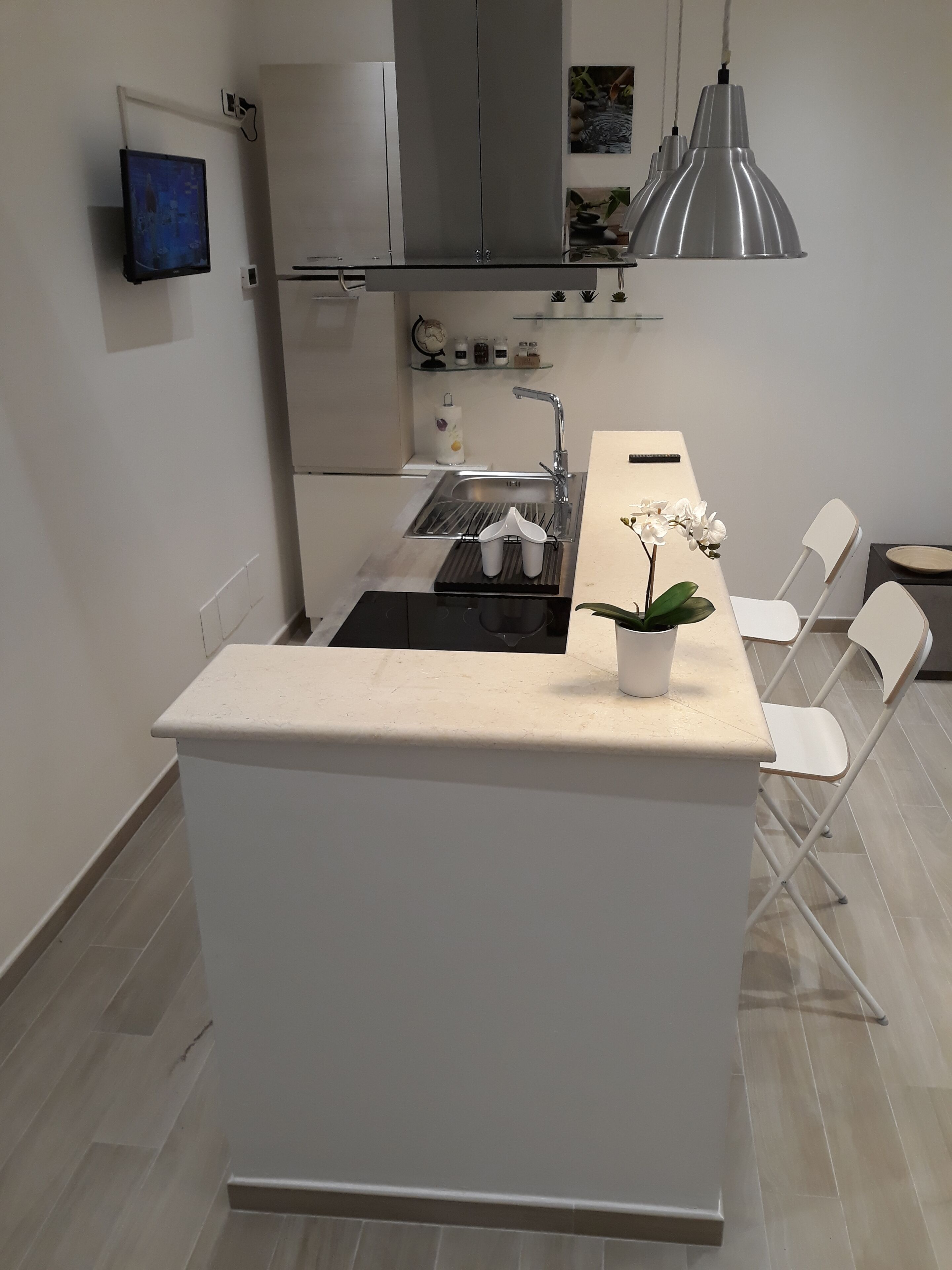 Una cocina moderna con una isla central, horno empotrado, fregadero y comedor con sillas.