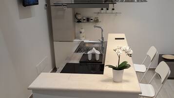Una cocina moderna con una isla central, horno empotrado, fregadero y comedor con sillas.