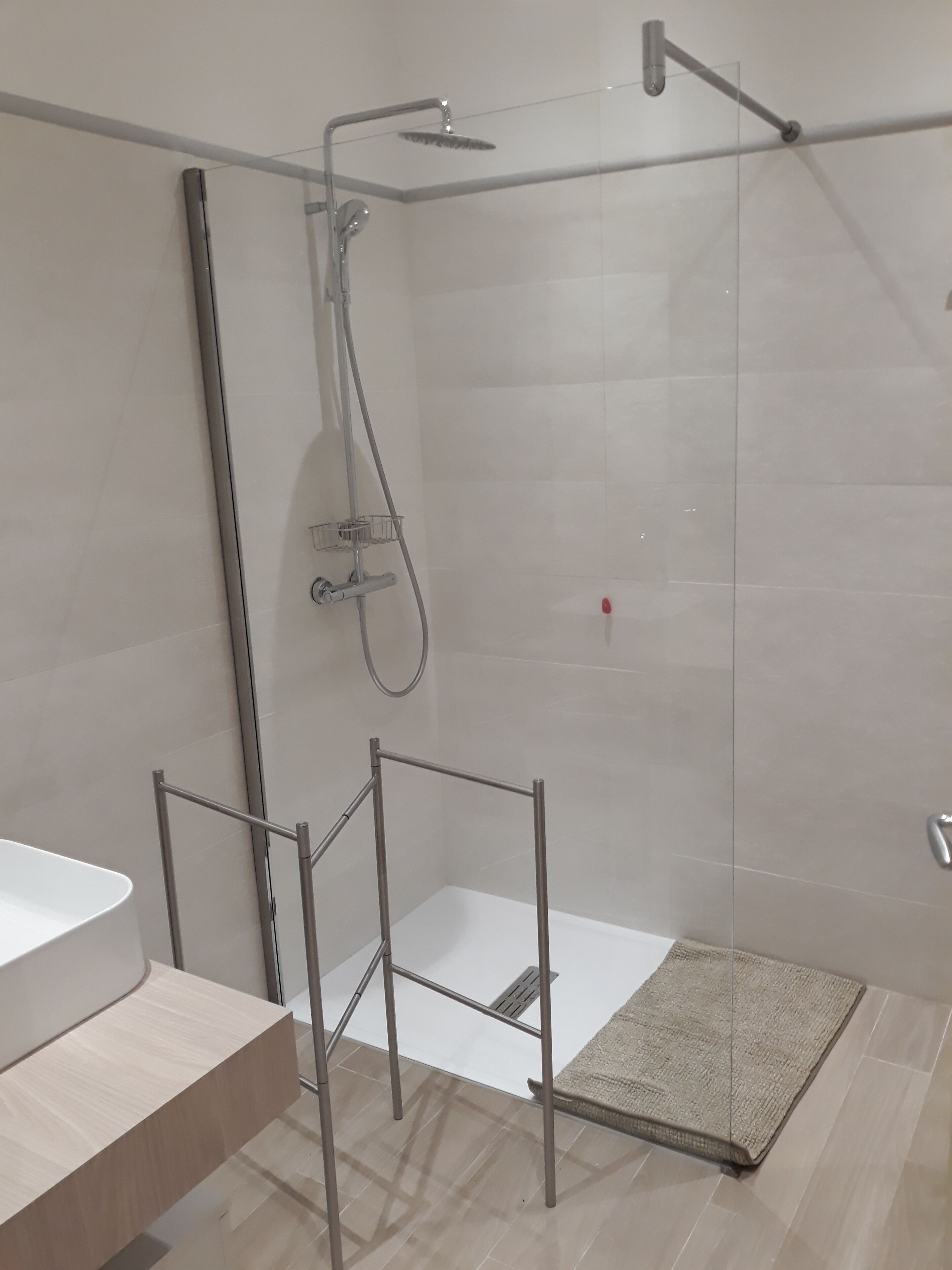 A modern bathroom with a glass shower enclosure, a white sink, and a wooden vanity.