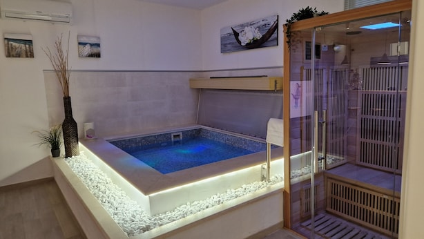 Une salle de bain moderne dotée d’un jacuzzi encastré, d’une douche en verre et d’œuvres d’art décoratives murales.