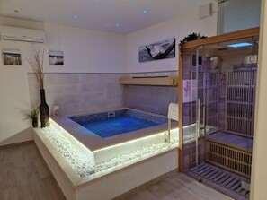 Een moderne badkamer met een ingebouwd whirlpoolbad, een douchecabine van glas en decoratieve wandkunst.