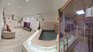 Une chambre d’hôtel moderne dotée d’un grand lit, d’un coin salon, d’une télévision et d’un petit espace piscine.