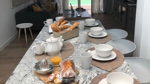 Ein moderner Essbereich mit einem langen Tisch, gedeckt für ein Frühstück mit Brot, Eiern und Saft.