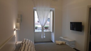 A bedroom with a bed, a TV, a window with curtains, and a balcony view. - La mia struttura (Palermo,)
