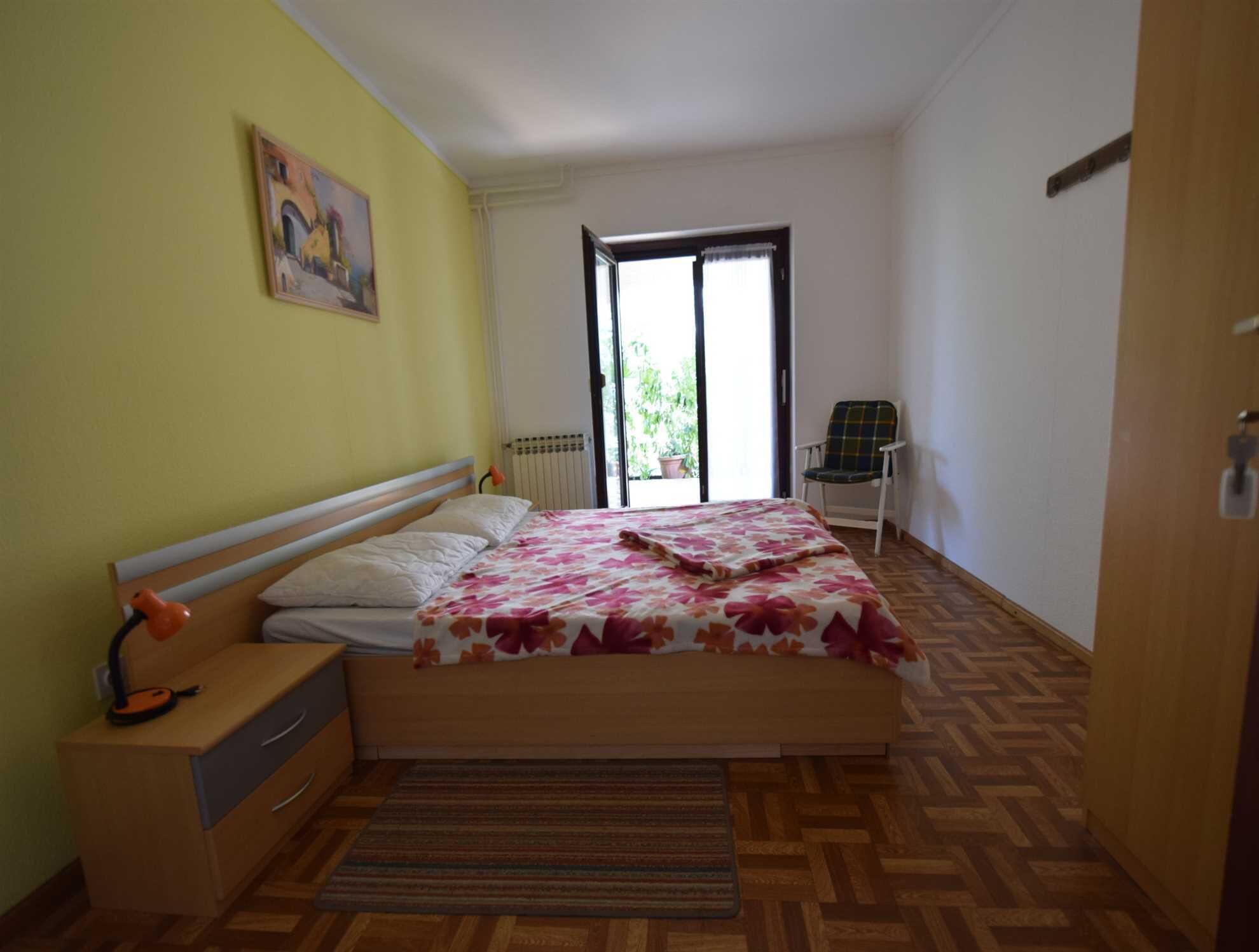 Un dormitorio con una cama, una silla, un radiador y una ventana.