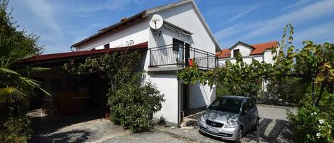 A two-story house with a satellite dish, a balcony, and a parked car.