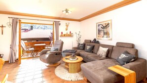 A living room with a sofa, armchairs, a coffee table, and a view through a glass door. - Ferienwohnung Elisabeth, 90 qm für 2-4 Personen (Reit im Winkl)