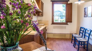 Eine Küche mit Holzausstattung, einem Fenster mit Blick und einem Tisch mit Blumen in einer Vase.