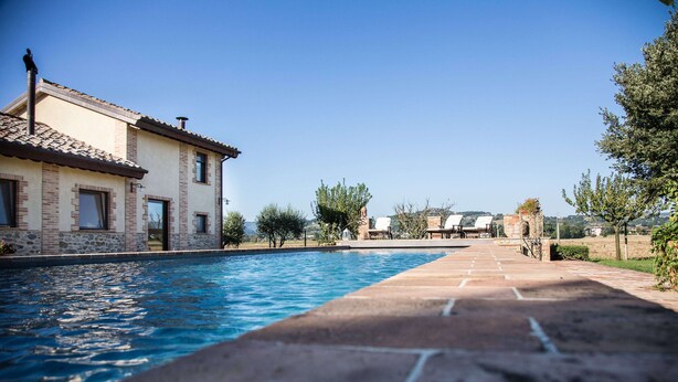 Ein Pool mit einer Steindecke, die zu einem Gebäude mit einem Ziegeldach und Backsteinmauern führt.