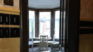 Ein Hotelzimmer mit Deckenventilator, einem Esstisch mit Stühlen und großen Fenstern.
