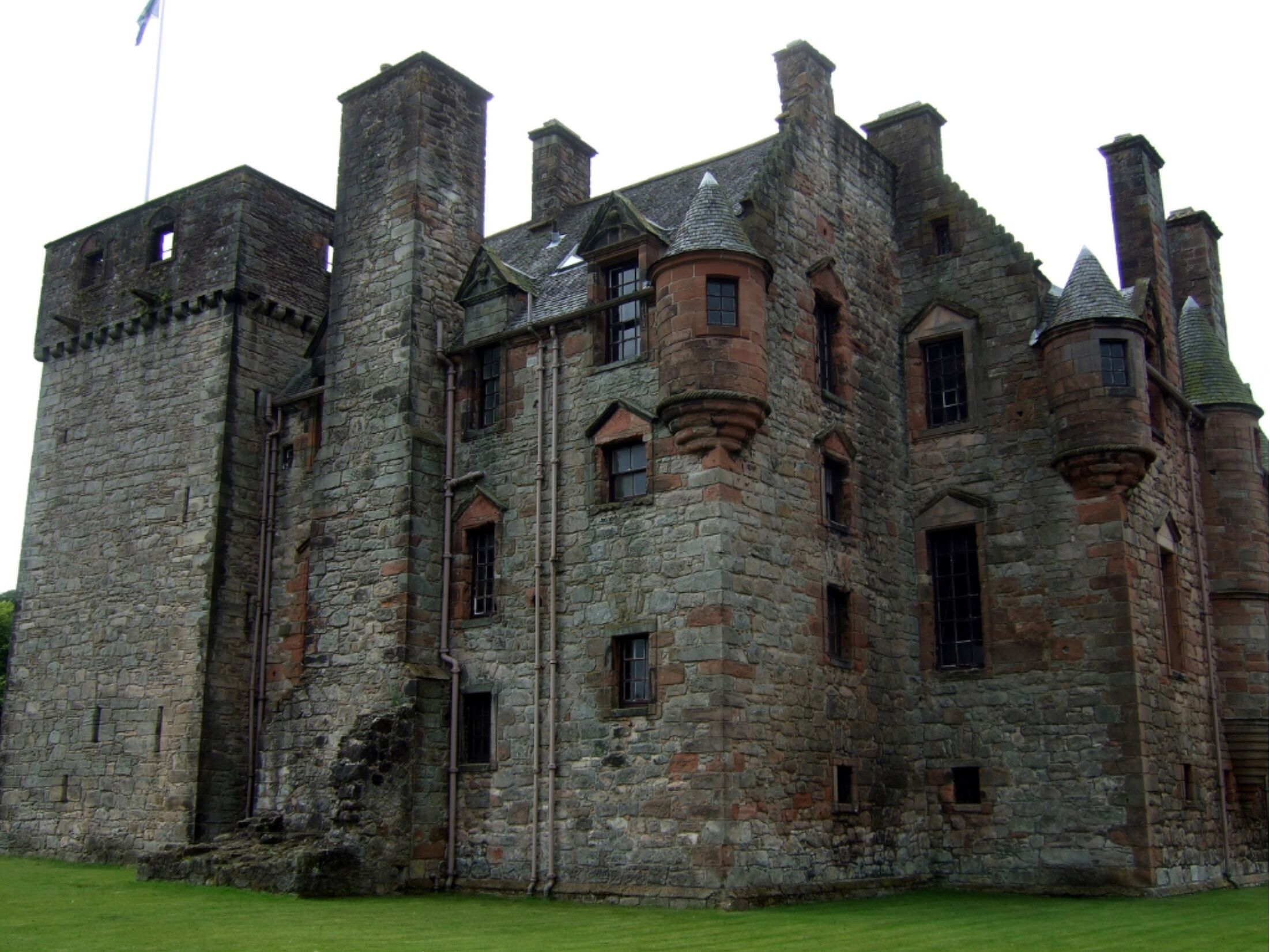 A historic stone castle with multiple towers and battlements, featuring a mix of stone and brick construction.
