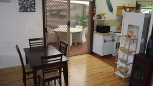 A compact kitchen with a dining area, a wooden table, chairs, a refrigerator, and a small oven. - Church St - Conveniently Located in the Hart of Bright (Bright)