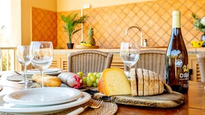 A dining table set with plates, glasses, cheese, bread, and a bottle of wine. - Es Recer by dracmallorca (Santanyi)