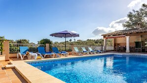 A swimming pool with lounge chairs and umbrellas, surrounded by a fence and trees. - Es Recer by dracmallorca (Santanyi)