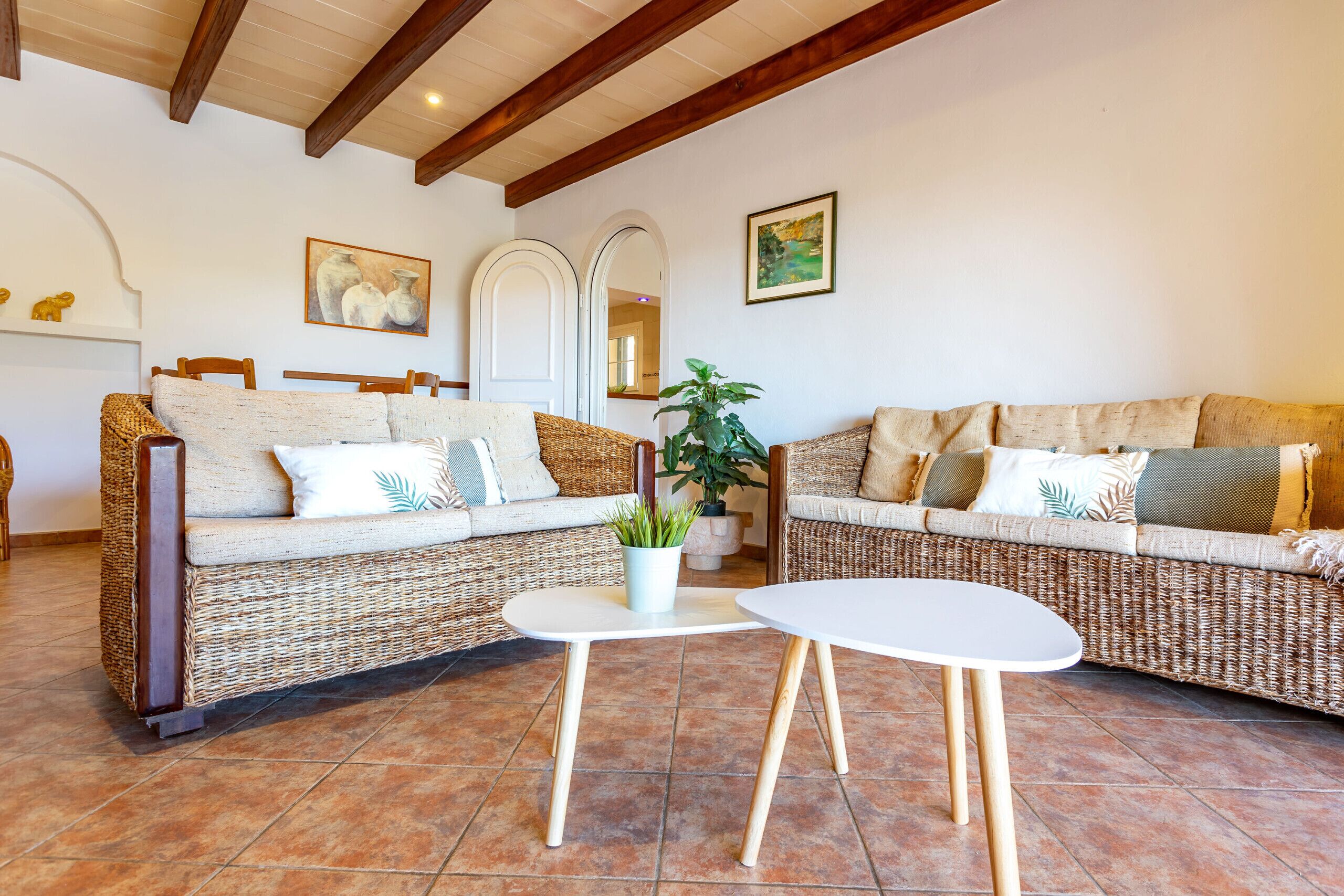 A living room with wicker sofas, a white table, and a potted plant.