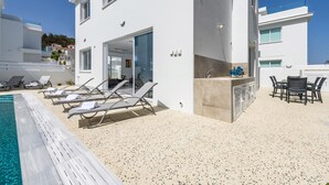 A modern villa with a pool, sun loungers, an outdoor kitchen, and a dining area. - Green Bay Villa #15 - Charming Green Bay Getaway (Protaras)