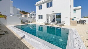 A modern white building with a swimming pool, sun loungers, and a covered outdoor area. - Green Bay Villa #15 - Charming Green Bay Getaway (Protaras)