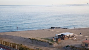 Una playa con un pequeño edificio, posiblemente un café o restaurante, cerca del agua.