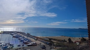 Un puerto deportivo con barcos amarrados, una playa y cielo despejado.