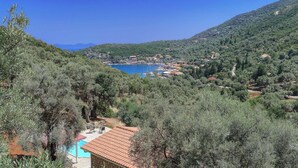 Un paysage côtier avec une piscine, des oliviers et une vue sur la mer.
