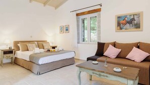 Une chambre à coucher avec un lit, des tables de chevet, une table basse en bois et un canapé.