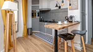 Uma cozinha moderna com mesa de madeira, banquetas e iluminação pendente.