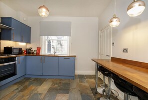 A kitchen with blue cabinets, a wooden countertop, and a window. - Patricks Pool Town House-4 Bed/4 Bath - sleeps 8 guests in 4 bedrooms (York)