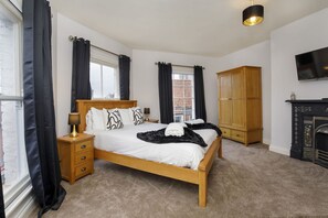 A bedroom with a wooden bed, a nightstand, a wardrobe, a fireplace, and a TV. - Patricks Pool Town House-4 Bed/4 Bath - sleeps 8 guests in 4 bedrooms (York)