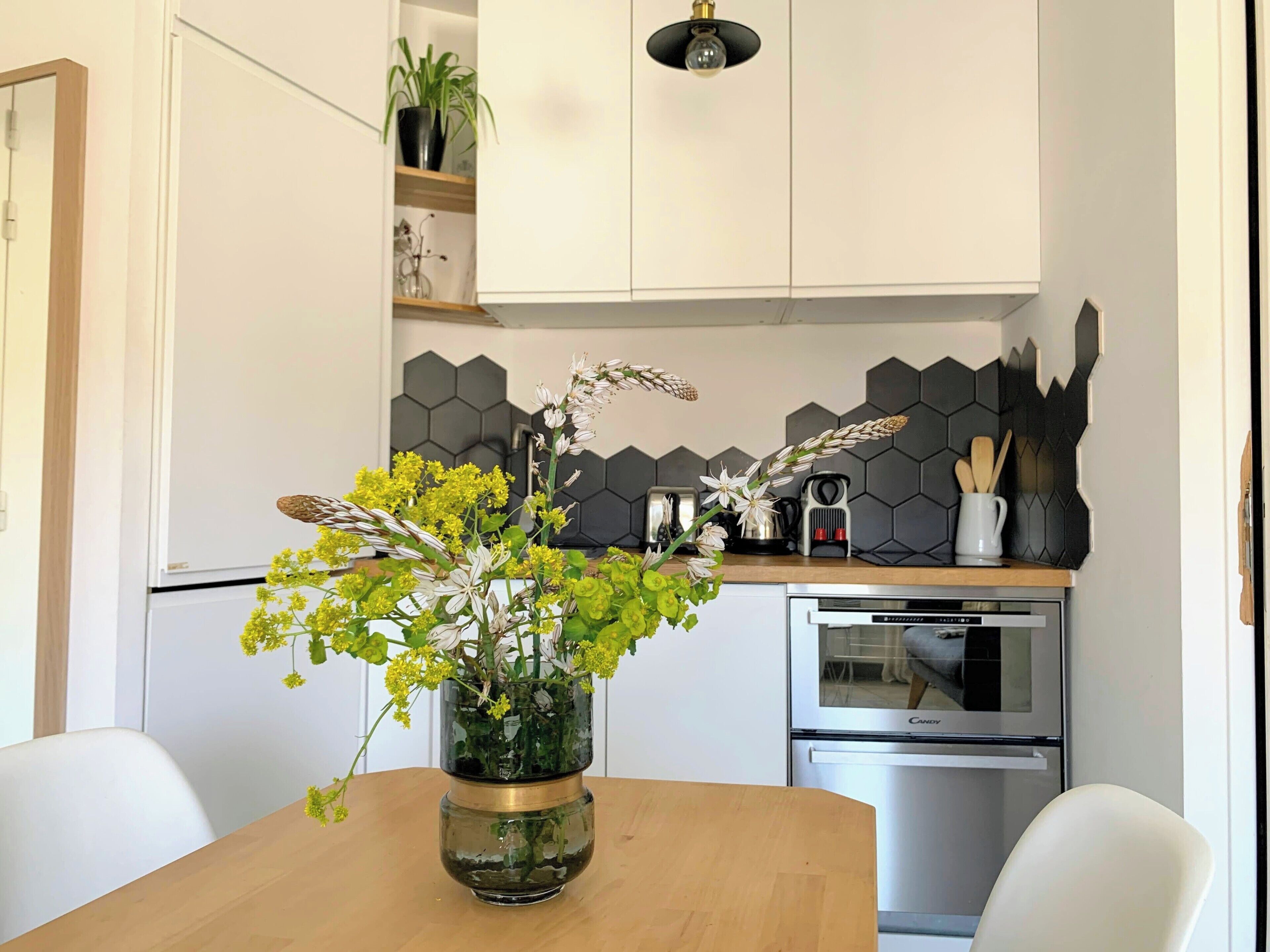 Una cocina moderna con armarios blancos, encimera de madera y horno empotrado.