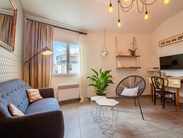 A modern living room with a sofa, chairs, a TV, and a large window. - Home Chic Home - Les Toits de l'Argenterie (Montpellier)