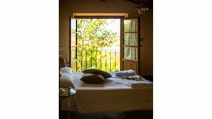 Ein Zimmer mit einem Bett, einem Sessel und einem Fenster mit Blick auf Grünflächen.
