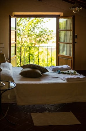 Une pièce avec un lit, une chaise et une fenêtre donnant sur un paysage verdoyant.