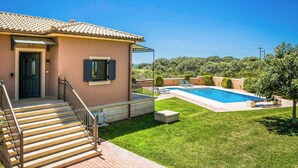 A house with a swimming pool, a covered patio, and a well-maintained lawn.