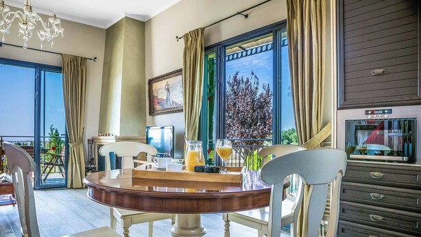 A dining area with a round table, chairs, and a view of the outdoors.