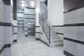 A modern interior with a marble staircase, glass doors, and pendant lighting.