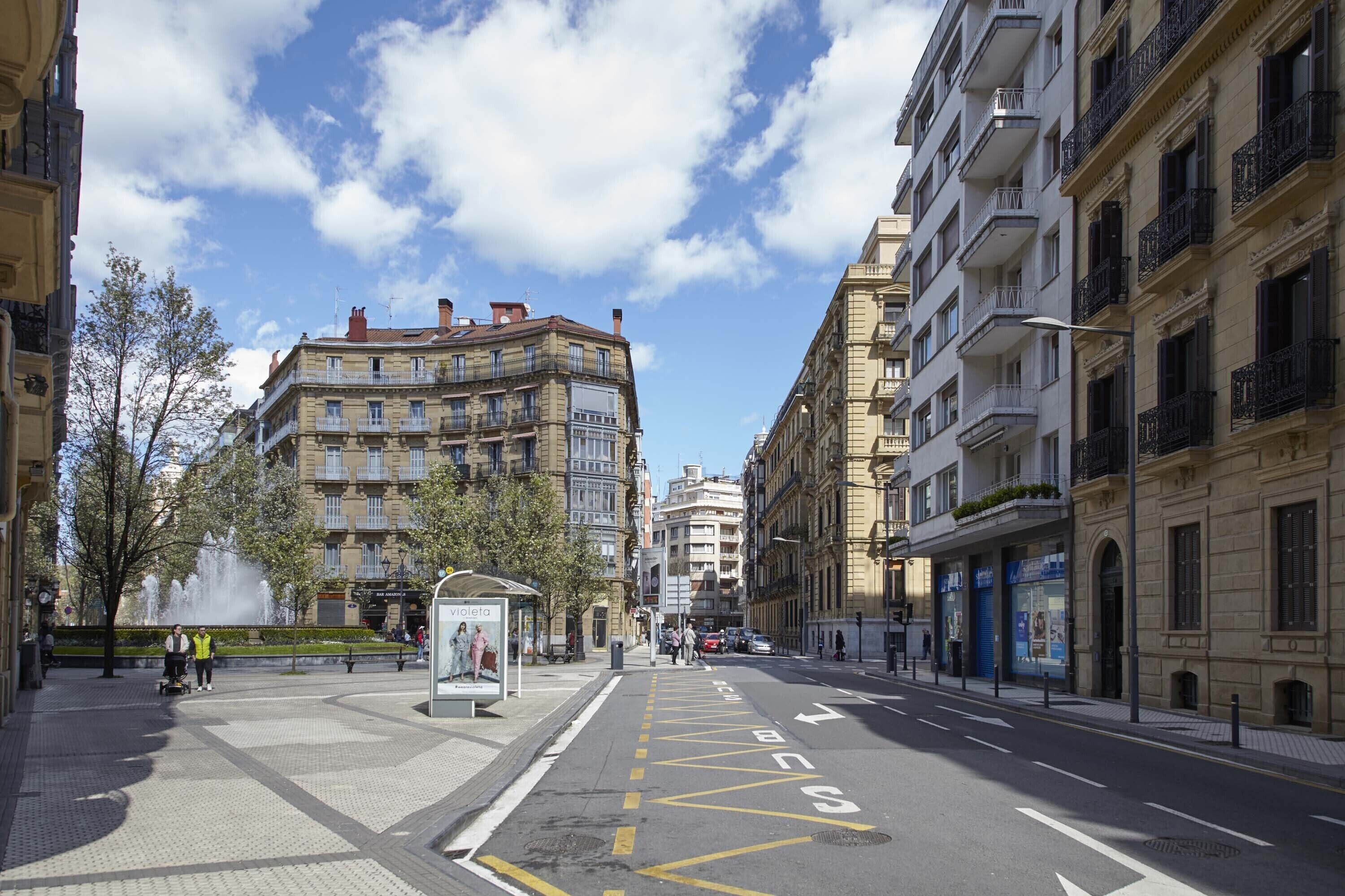 Une rue de la ville avec des immeubles, une fontaine et un arrêt de bus.