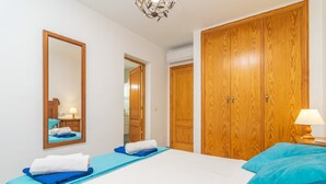 A hotel room with a large bed, a wooden wardrobe, a mirror, and a nightstand with a lamp. - CASA HECTOR - Villa with private pool in Cala d'Or. Free WiFi (Santanyí)