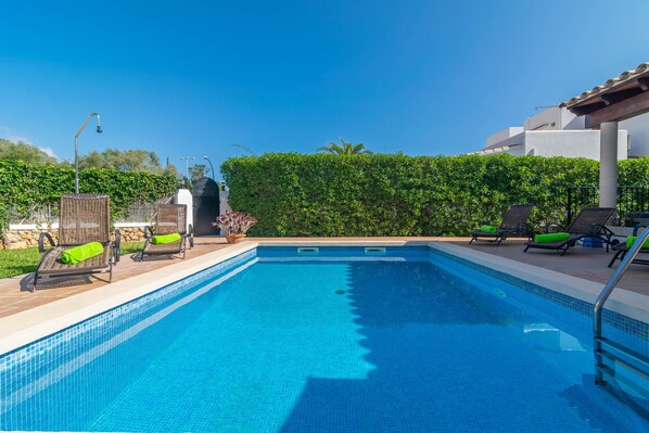 Una piscina con sillones de descanso y una pérgola.