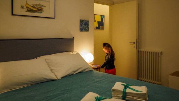 Une chambre d’hôtel avec un lit, une table de chevet, une lampe et une porte donnant sur une autre pièce.