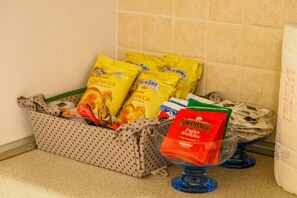 A kitchen area with a polka-dotted storage basket containing various food items and a glass bowl with a red packet labeled "TWININGS English Breakfast." - Casa Pina Quiet Apartment (Vernazza)