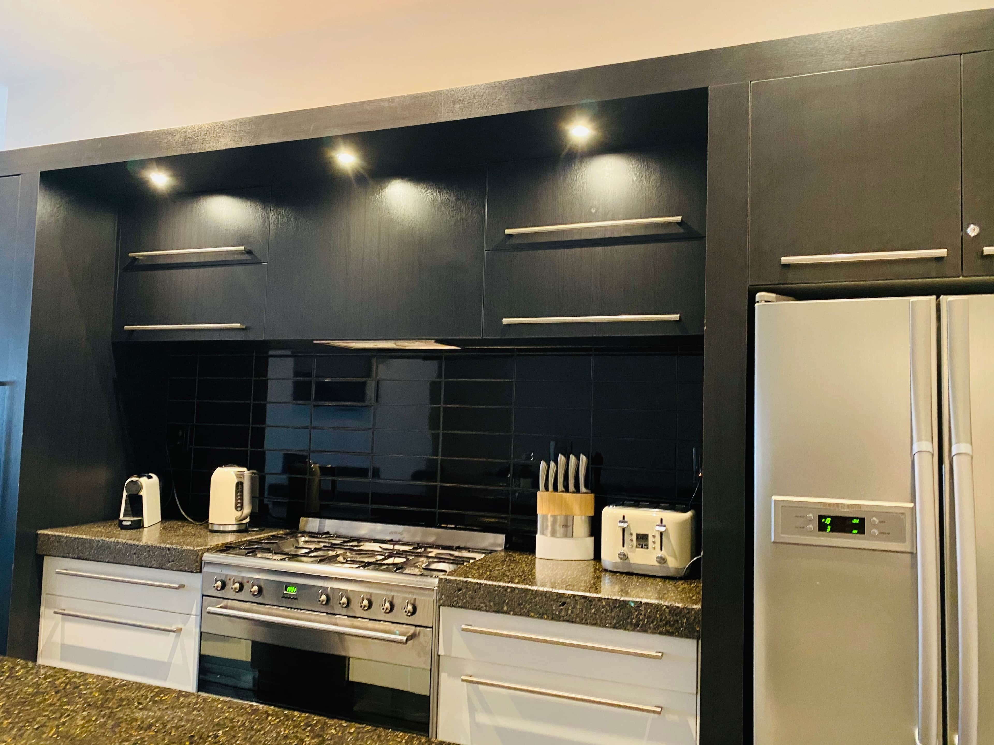 A modern kitchen with a gas stove, a built-in oven, a refrigerator, and a toaster on the countertop.