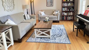 Uma sala de estar com sofá, mesa de centro, estante de livros e um piano.