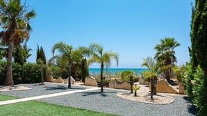A landscaped garden with palm trees, a pathway, and a view of the sea.