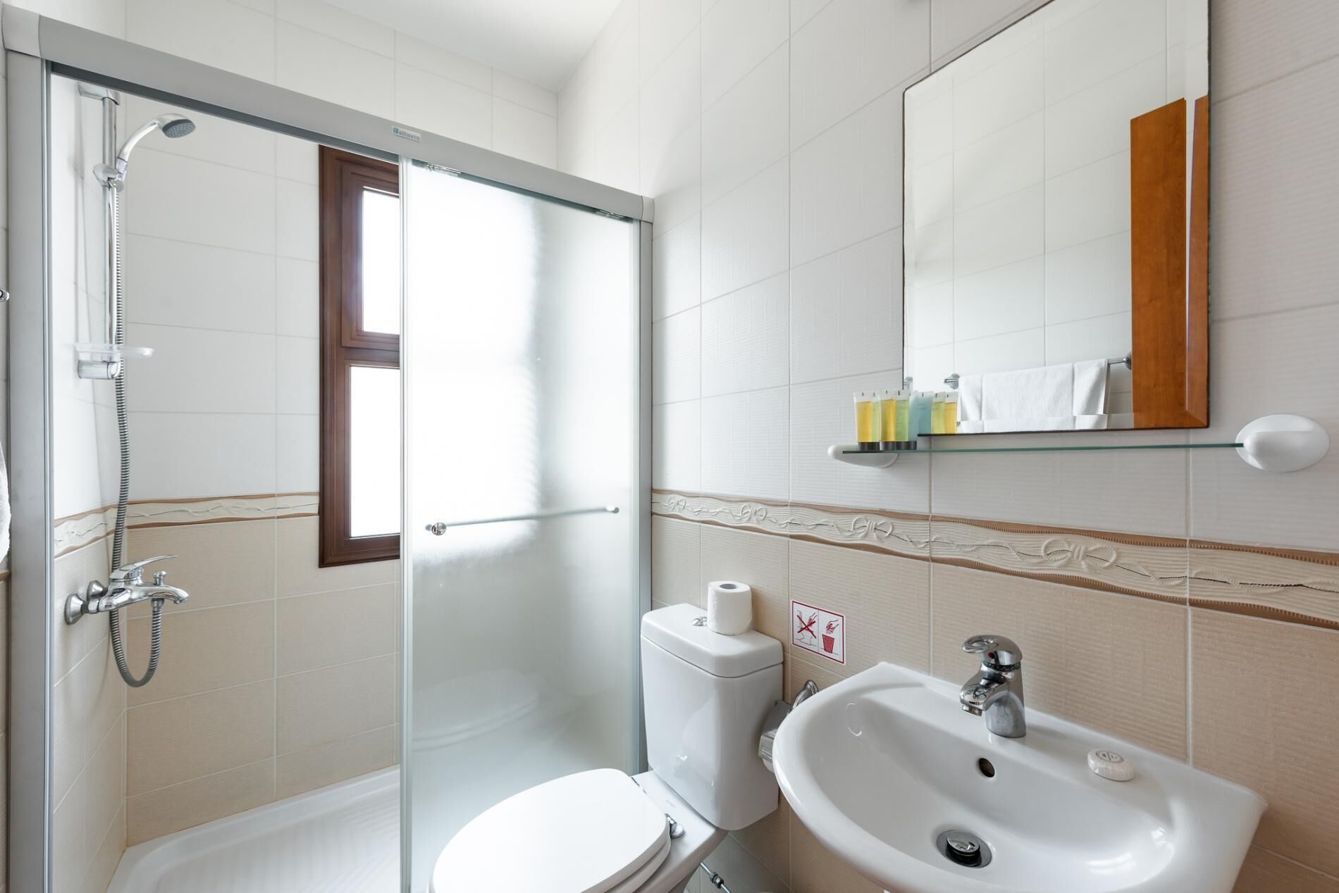 Un bagno con doccia vetrata, un water, un lavandino e uno specchio.