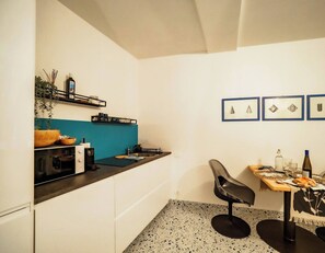Cocina compacta con encimera, lavamanos y zona de comedor con una silla y mesa.