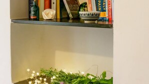 A bookshelf with books, a candle, and a decorative bowl.